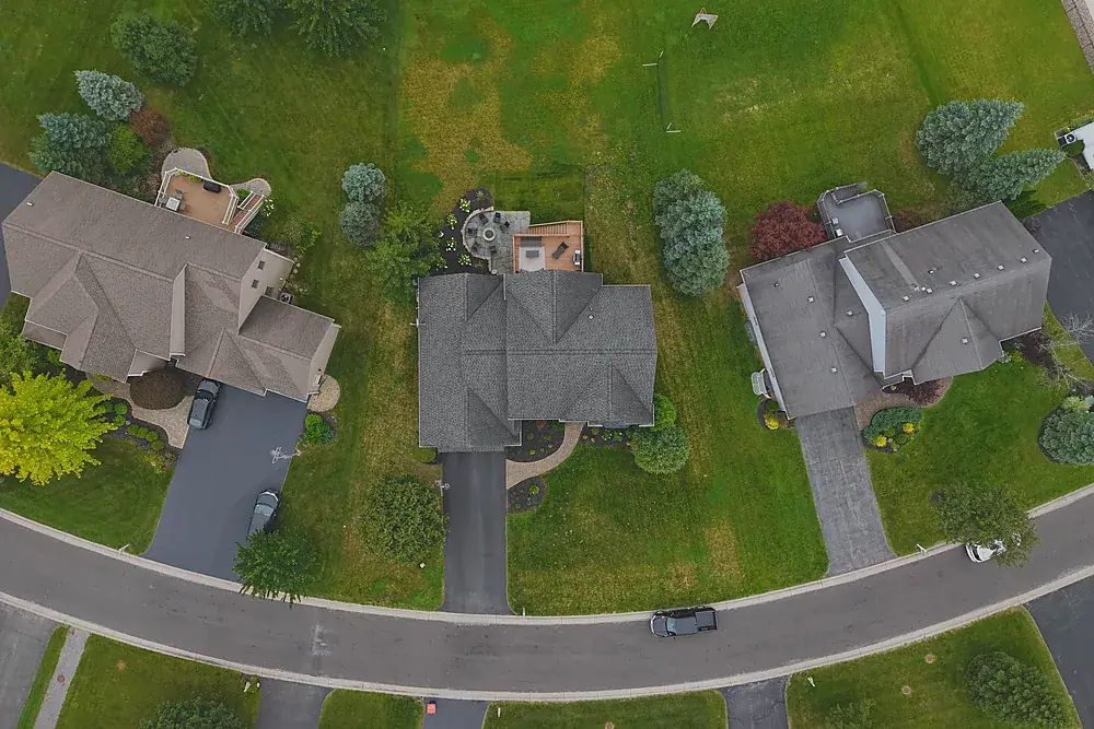 Overhead drone view of rooftops and driveways in a Rochester, New York neighbourhood