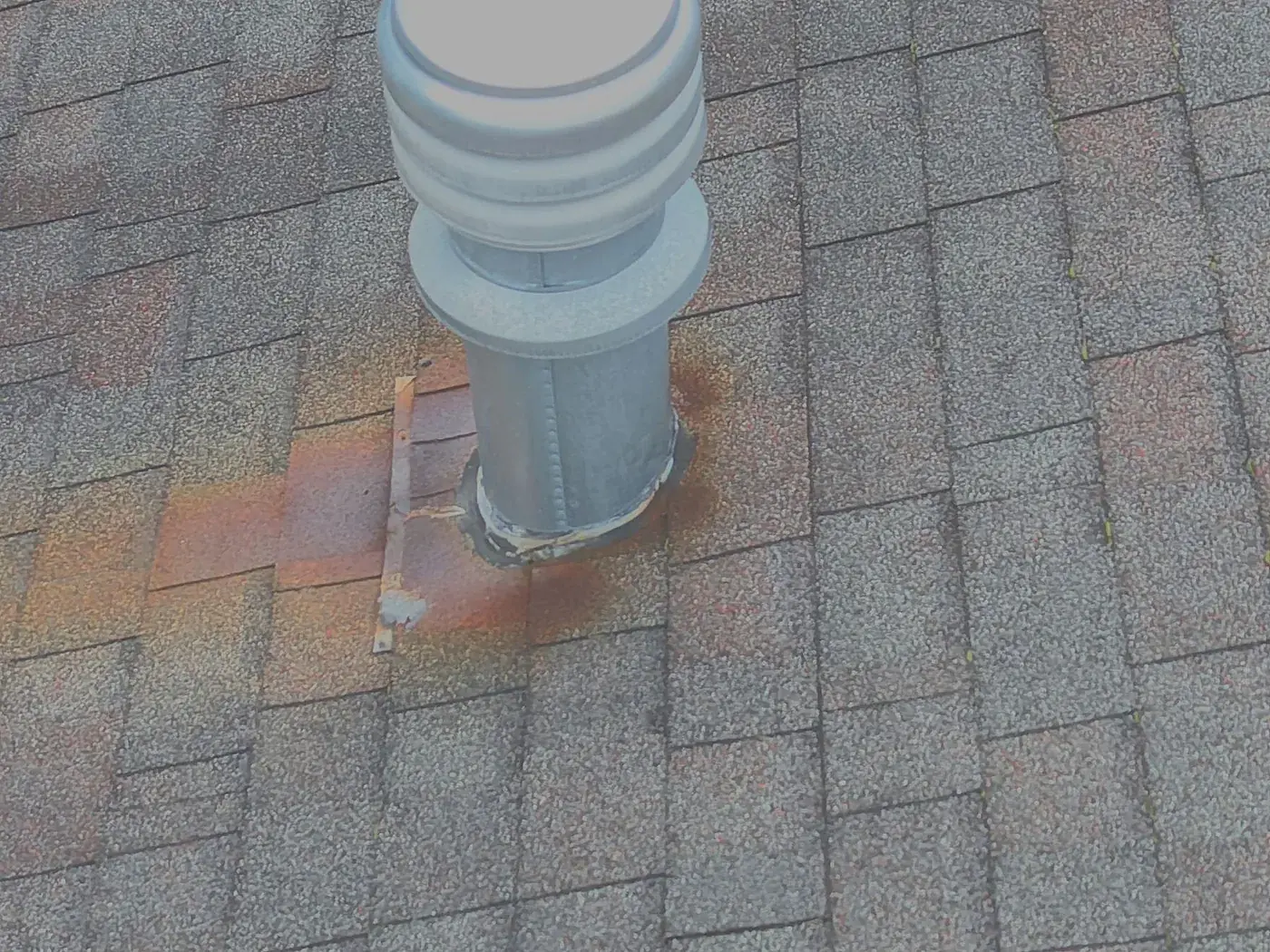 Close-up aerial photo of rust staining around a roof vent stack