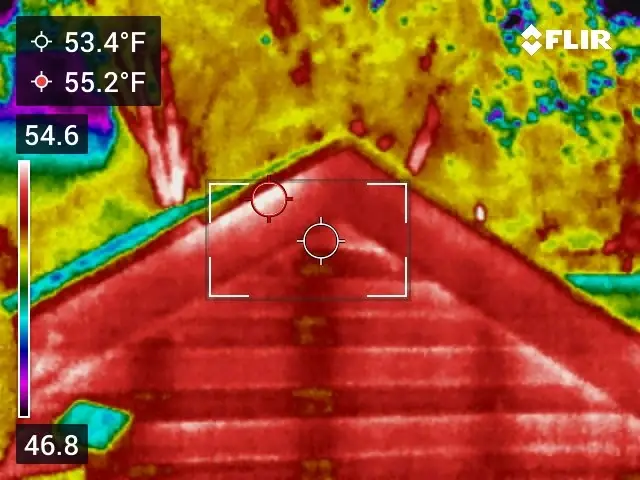 Thermal image of a roof peak and gable at night against a cooler sky and trees
